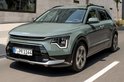 Een lichtgroene Kia Niro rijdt over een straat, de voorkant is duidelijk zichtbaar.