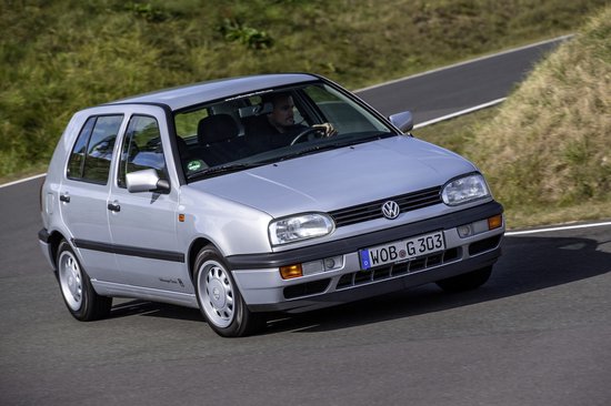 Volkswagen Golf 3 argentée roulant sur une route extérieure.