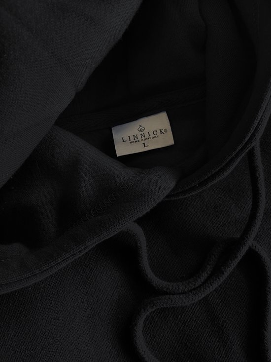 Detailopname van de binnenkant van een zwarte LINNICK hoodie met label.