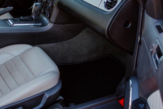Tapis de voiture noir sur le sol d'une voiture à côté d'un siège en cuir gris.
