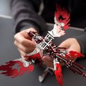 Gedetailleerd zilveren en rood metalen feniks model, vastgehouden door handen, met gevlamde vleugels en staart.