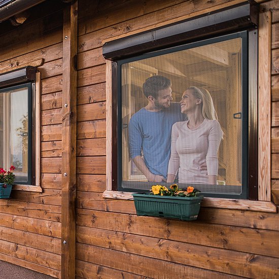 Een koppel staat in de deuropening van een houten huis, kijkend door een horraam.