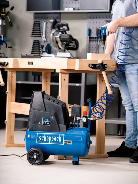 Blauwe Scheppach compressor met 24L tank, 1.5 PK, in een werkplaats. Een man gebruikt een blaaspistool.