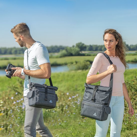 Man en vrouw met grijze cameratas in landelijke omgeving.