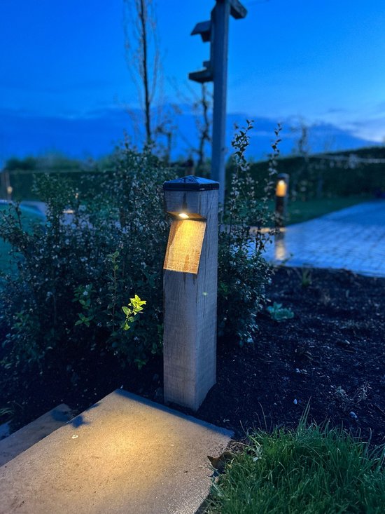 Houten tuinpaal 'Classica' met een lamp die naar beneden schijnt, aan de rand van een pad.