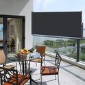 Donkergrijs uitklapbaar tuinscherm op een balkon met een tafel en stoelen.