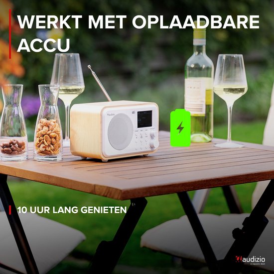 Retro radio met witte voorkant en houten zijkanten, op een tafel buiten met drankjes.