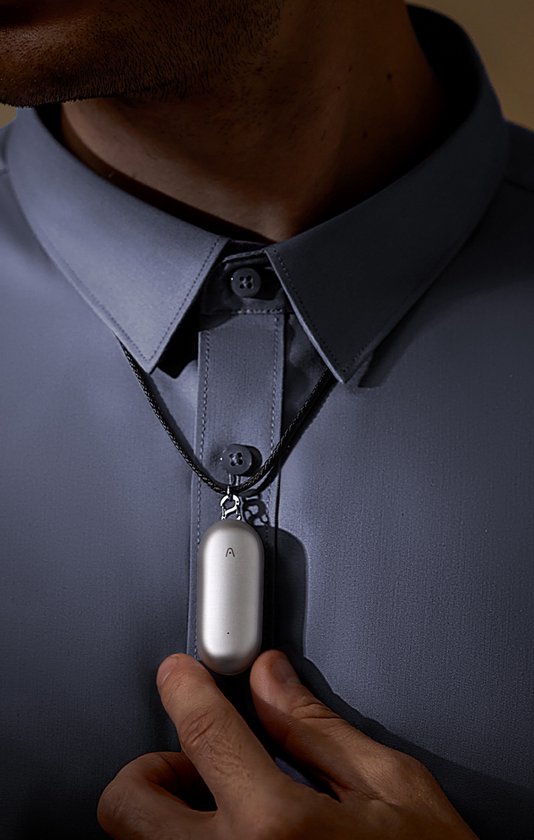 Man in grijs overhemd met de zilverkleurige Plaude NotePin als ketting.