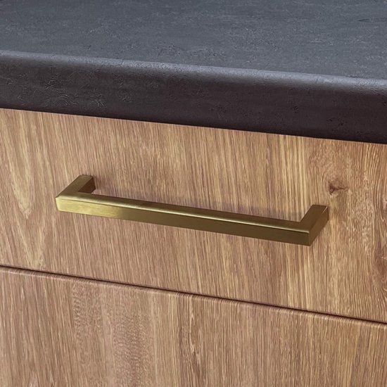 Gouden handgreep op een houten kastdeur onder een zwart werkblad.