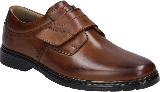 Zijkant van een bruine leren schoen met klittenbandsluiting en een zwarte zool.