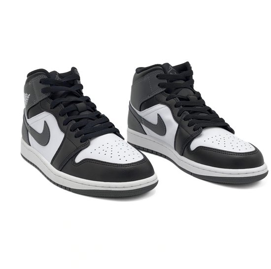 Twee witte Nike Air Jordan 1 Mid sneakers met zwarte en grijze overlays.