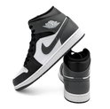 Een witte Nike Air Jordan 1 Mid sneaker met zwarte en grijze accenten en een logo.
