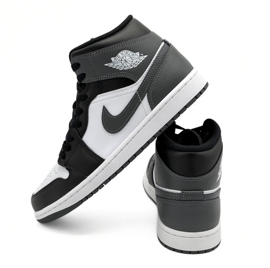 Een witte Nike Air Jordan 1 Mid sneaker met zwarte en grijze accenten en een logo.