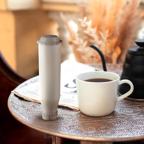 Grijs koffiefilter naast een kop koffie op een sierlijk dienblad.