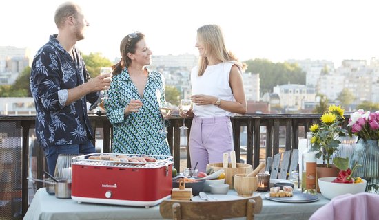 Man en twee vrouwen genieten van een barbecue met rode tafel BBQ en drankjes.