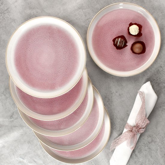 Een stapel van vijf roze borden met een crèmekleurige rand en een gespikkelde textuur. Bovenop liggen drie bonbons.