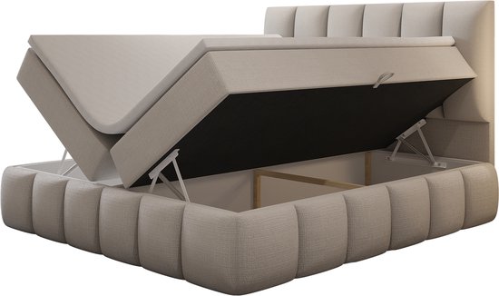 Beige boxspring met openklapbaar matras voor opbergruimte. Gestoffeerde basis met verticale strepen.