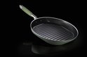 Groene grillpan met ribbels aan de binnenkant en een lichtgroene handgreep, op zwarte achtergrond.