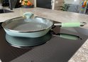Lichtgroene grillpan met deksel op een inductiekookplaat.