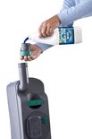 Hand die Thetford Aqua Kem Blue vloeistof in een doseerbeker giet voor een chemisch toilet.