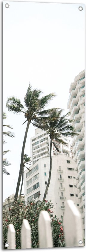 Tuinposter – Wind door Palmbomen bij Wit Gebouw - 40x120 cm Foto op Tuinposter (wanddecoratie voor buiten en binnen)