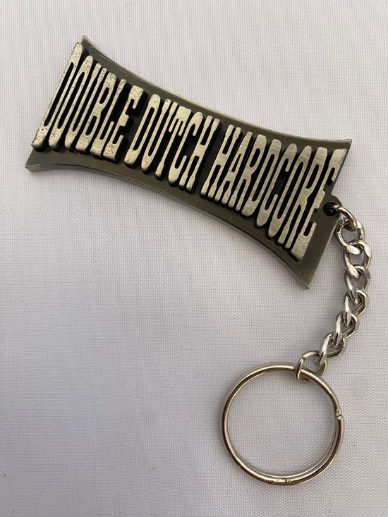 Zilverkleurige sleutelhanger met de tekst 'DOUBLE DUTCH HARDCORE' op een gebogen plaatje.