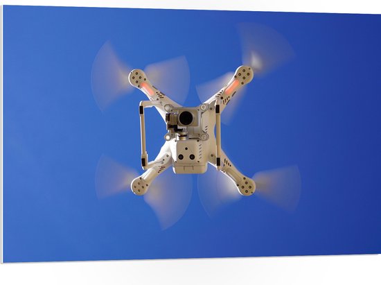 PVC Schuimplaat- Onderaanzicht van Vliegende Drone onder Blauwe Lucht - 105x70 cm Foto op PVC Schuimplaat
