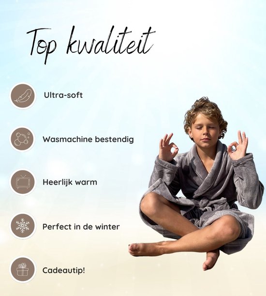 Jongen in een grijze fleeced badjas, zittend in meditatie op het strand.