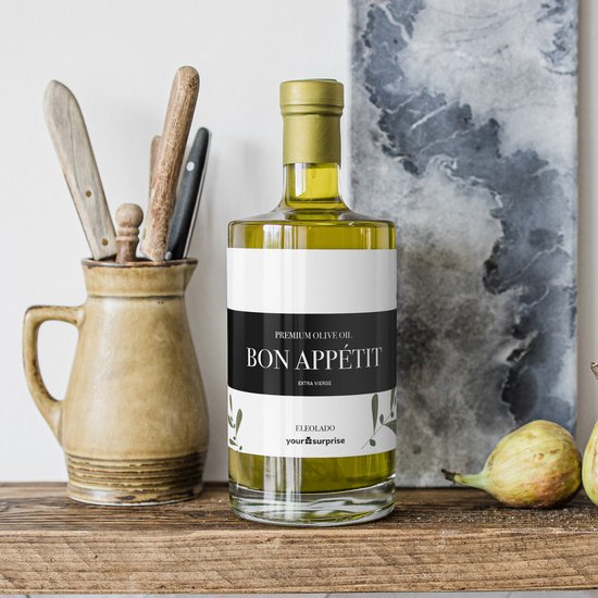 Een glazen fles olijfolie met het etiket "BON APPÉTIT" en "PREMIUM OLIVE OIL". Op een houten plank, met keukengerei en vijgen.