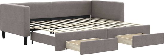 Grijze slaapbank met uitgetrokken bed en vier open lades, met houten latten.