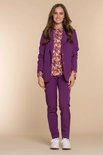 Model draagt een paarse Geisha blazer en broek met een veelkleurig blouse met geometrisch patroon. Witte sneakers eronder.