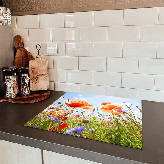 Een inductiebeschermer met klaprozen en korenbloemen op een aanrecht.