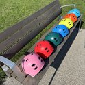 Six casques PRO Sport Lights de différentes couleurs sur un banc en bois.