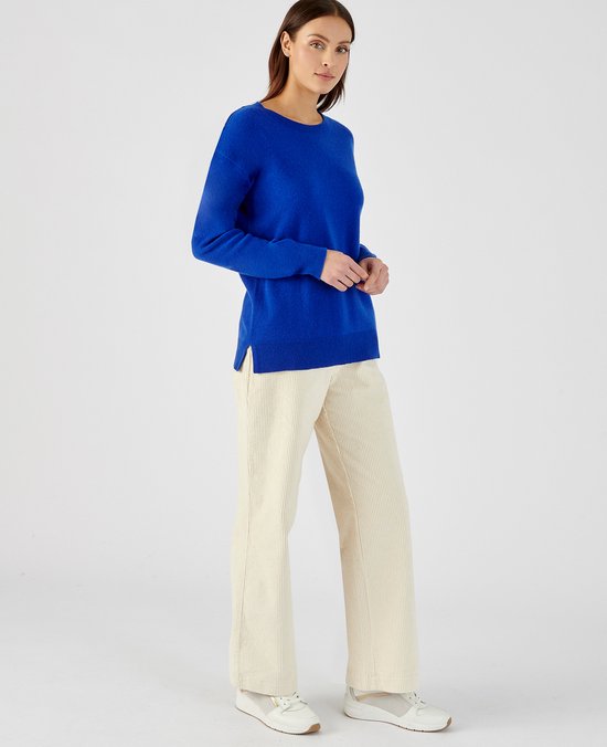 Model draagt een kobaltblauwe kasjmieren trui met ronde hals, gecombineerd met crème corduroy broek.