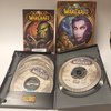 World of Warcraft gamebox met een ork-afbeelding, PC gamebox met elf-achtige vrouw, en geopende cd-box met 7 cd's.