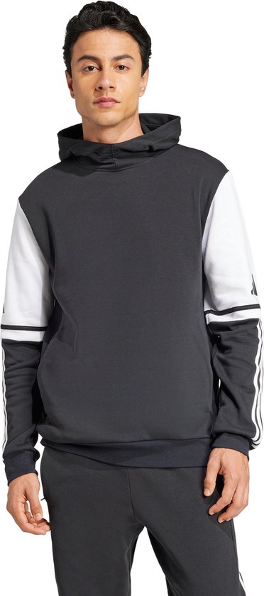 Man met een donkergrijze capuchontrui. De trui heeft witte mouwen met zwarte Adidas-strepen.