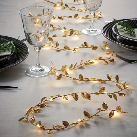 Guirlande lumineuse à feuilles dorées avec lumières LED blanc chaud sur une table dressée.