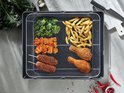 Grillmand vol met frietjes, kip, zoete aardappelschijfjes en groenten.