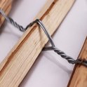 Detail van twee houten palen verbonden door verdraaid metaaldraad. Naturel hout.