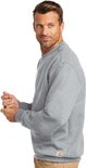 Man in een grijze crewneck sweater van Carhartt, staand, met beige cargo broek.