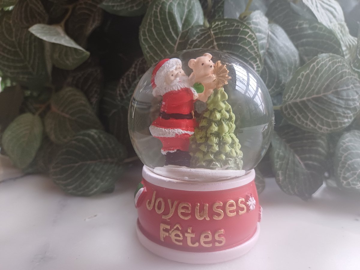 Sneeuwbol met kerstman, kerstboom, teddybeer en rode sokkel.