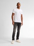 Man draagt een witte t-shirt en zwarte slim fit jeans met vintage wassing.