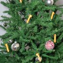 Gouden piemel kersthanger versierd aan een kerstboom met zilveren kerstballen.