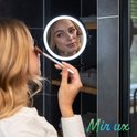 Vrouw met blonde haren, die make-up aanbrengt met een kwast in een Mirlux led make-up spiegel.
