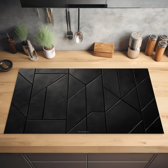 Zwarte inductiebeschermer met geometrisch tegelpatroon op een houten aanrecht.