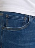 Detail van de voorkant van een blauwe spijkerbroek met een coin pocket, rits en knoopsluiting.