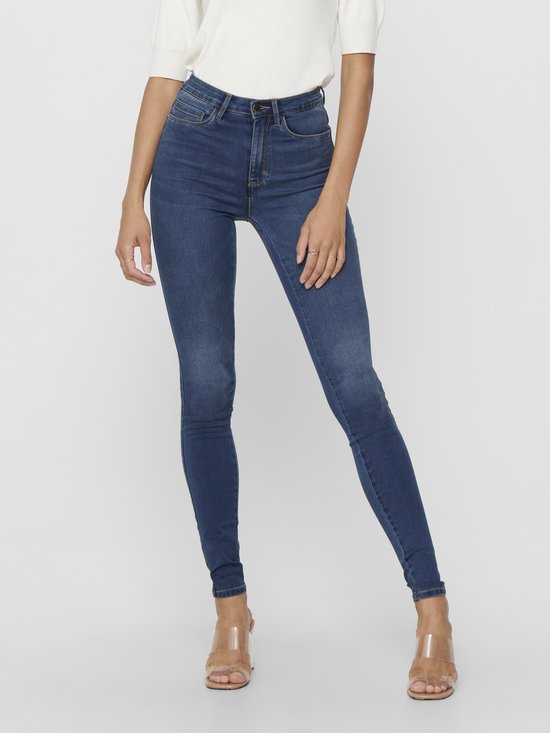 Model in een aansluitende, donkerblauwe skinny jeans met hoge taille.
