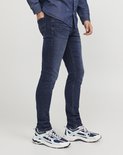 Blauwe skinny jeans gedragen door een man met spierwitte sneakers en een spierwitte denim blouse.