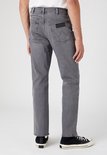 Man, van achteren gezien, in een grijze jeans. Hij draagt zwarte sneakers.