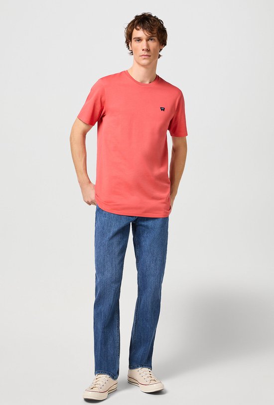 Man in een oranje T-shirt en blauwe spijkerbroek.